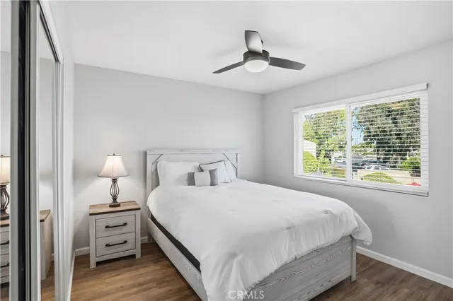 a bedroom with a bed a window and potted plant on the dresser