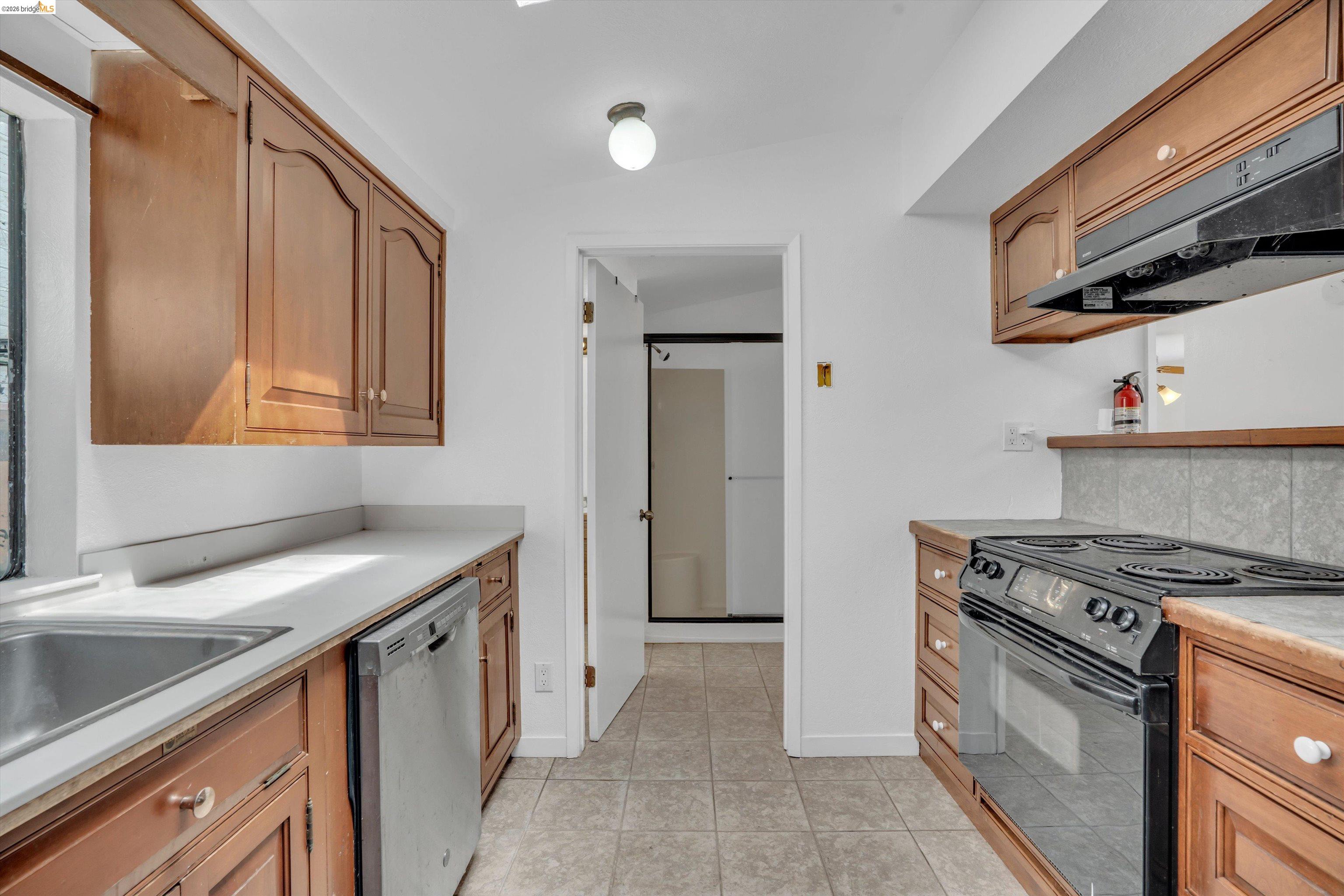 1922 Taylor Road Bethel Island, CA 94511 - Photo 28 of 49 Kitchen with light countertops, black range with electric cooktop, stainless steel dishwasher, exhaust hood, and light tile patterned floors