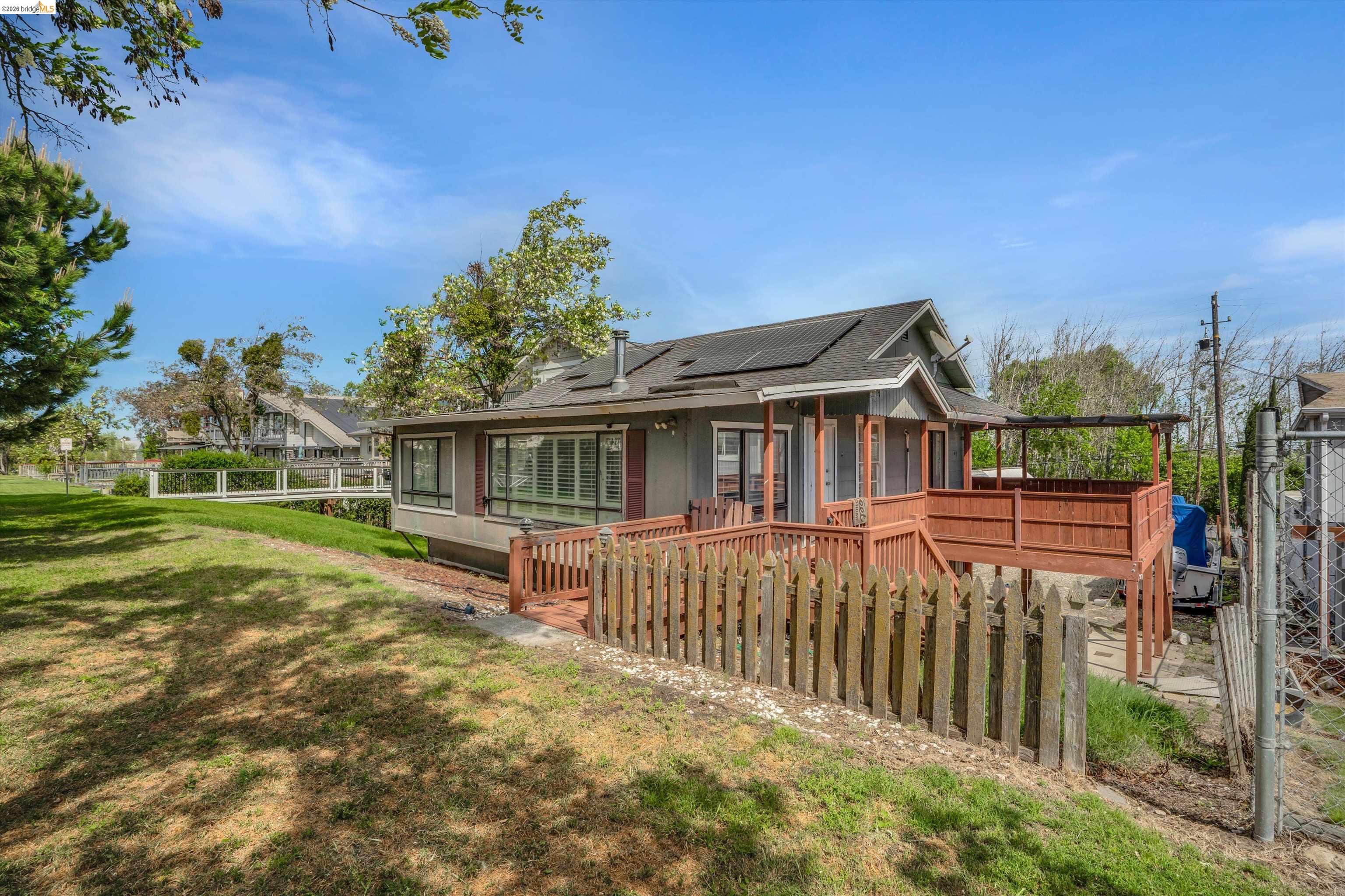 1922 Taylor Road Bethel Island, CA 94511 - Photo 48 of 49 View of side of home with roof mounted solar panels, a wooden deck, and roof with shingles