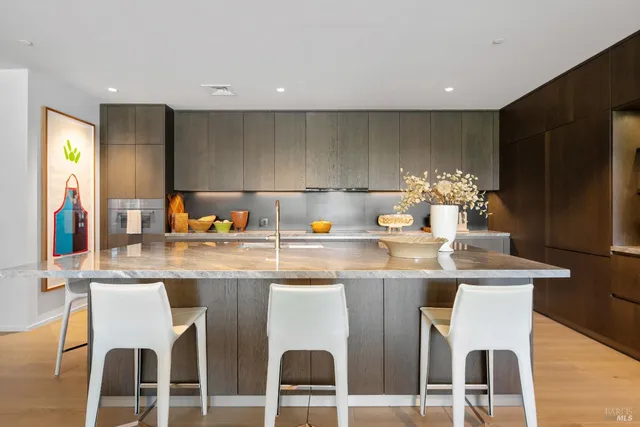 a kitchen with a dining table chairs and white cabinets with wooden floor