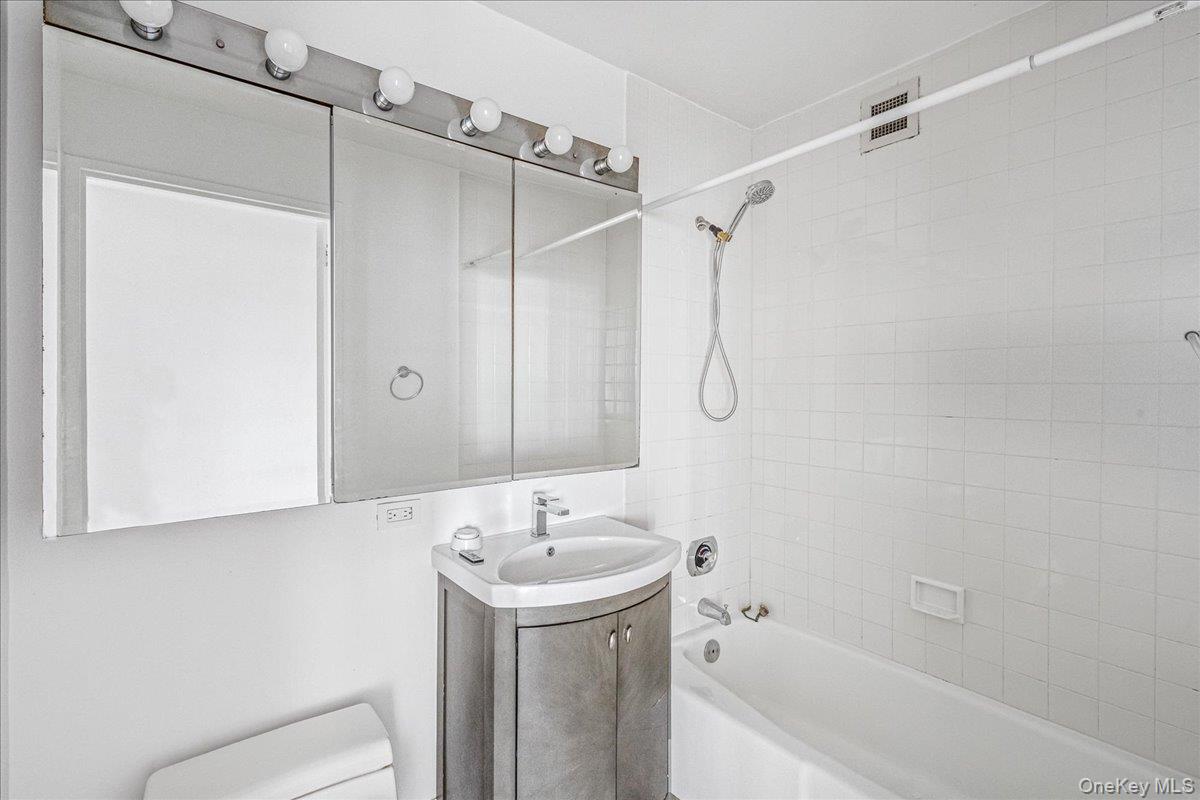 112-01 Queens Boulevard, Unit 23C Queens, NY 11375 - Photo 21 of 32 a bathroom with a sink a mirror and a shower