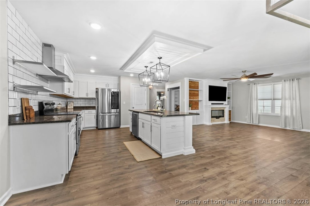 83 Kotata Avenue Bunnlevel, NC 28323 - Photo 24 of 49 a kitchen with stainless steel appliances kitchen island granite countertop a refrigerator a stove top oven a sink dishwasher and white cabinets with wooden floor