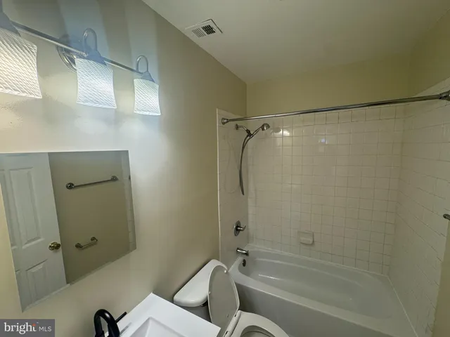 a bathroom with a granite countertop bathtub shower sink vanity and toilet