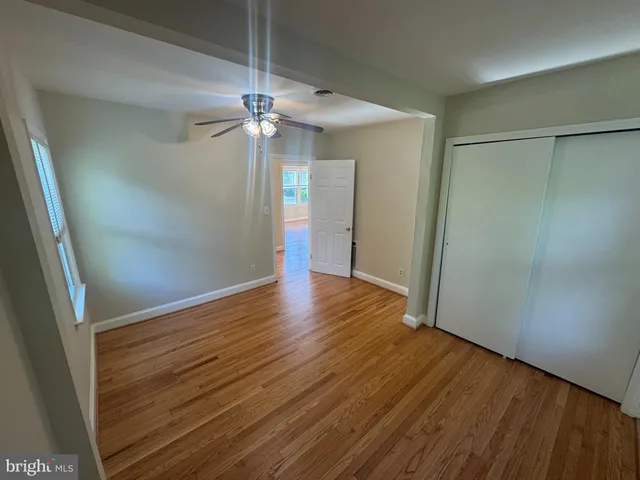 an empty room with wooden floor a ceiling fan and staircase