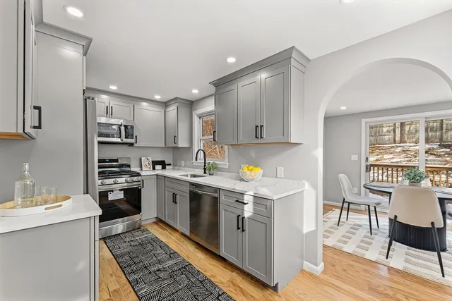 a kitchen with a stove a sink dishwasher a refrigerator and white cabinets with wooden floor