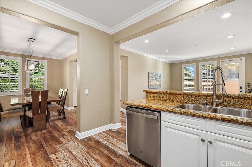 12 Globe Lane Ladera Ranch, CA 92694 - Photo 13 of 37 a kitchen with granite countertop a stove a dining table and chairs with wooden floor