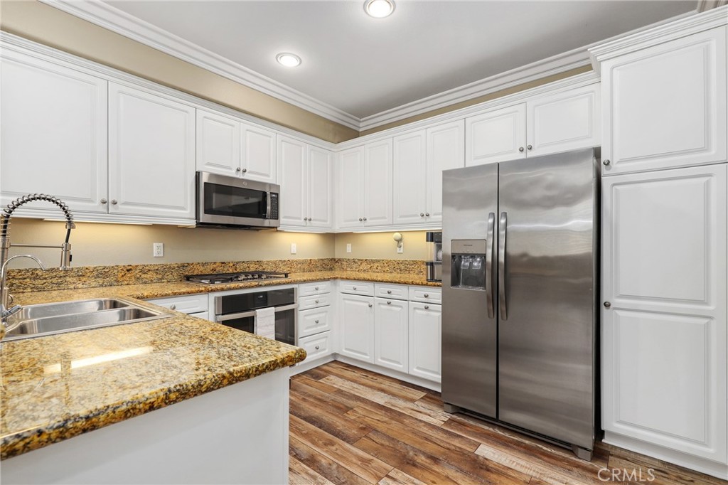12 Globe Lane Ladera Ranch, CA 92694 - Photo 15 of 37 a kitchen with stainless steel appliances granite countertop a refrigerator a stove a sink and white cabinets with wooden floor