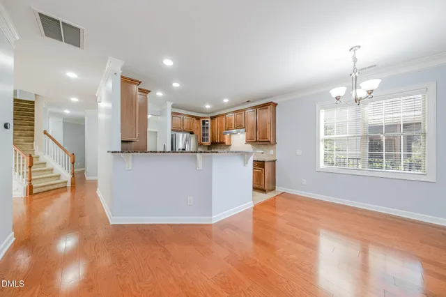 a view of a large kitchen with stainless steel appliances granite countertop a stove and a wooden floors