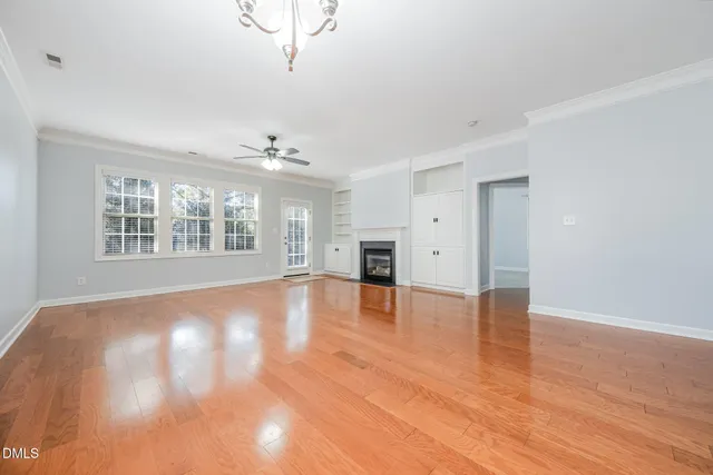 a view of an empty room with a window and wooden floor