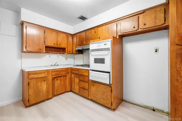 a kitchen with stainless steel appliances granite countertop wooden cabinets a sink a stove a washer dryer and a refrigerator