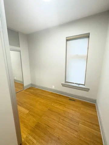 a view of empty room with window and hardwood floor