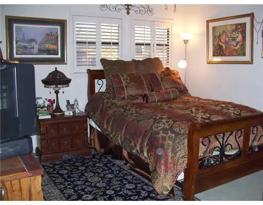 a bed sitting in a bedroom next to a window with painting on the wall