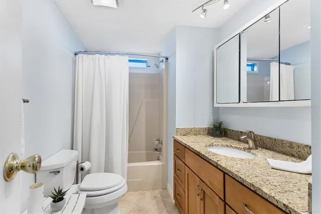 a bathroom with a granite countertop sink a toilet and shower