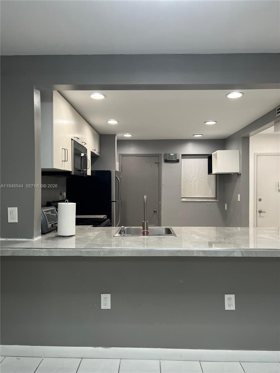 1710 Northeast 191st Street, Unit 1003 Miami, FL 33179 - Photo 5 of 16 a view of kitchen with kitchen island sink and refrigerator