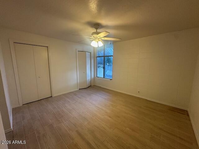 1101 East Bethany Home Road, Unit 16 Phoenix, AZ 85014 - Photo 13 of 15 an empty room with a ceiling fan and wooden floor