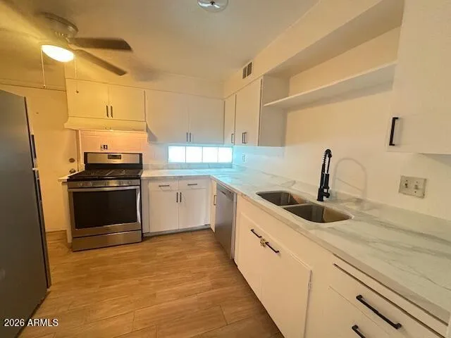 a kitchen with granite countertop a sink and white cabinets