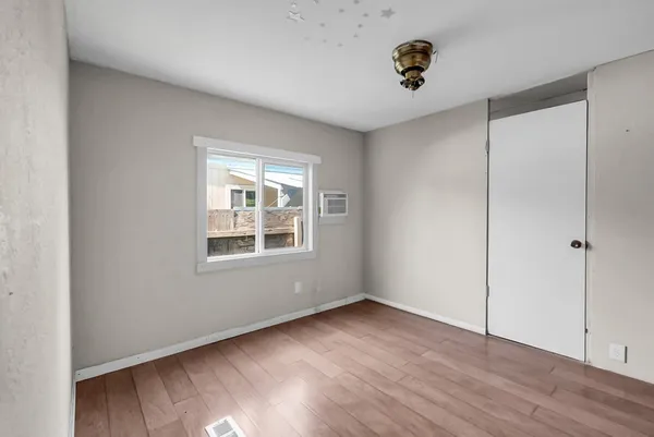 a view of an empty room with wooden floor and a window