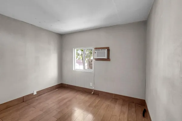 a view of an empty room with wooden floor and a window