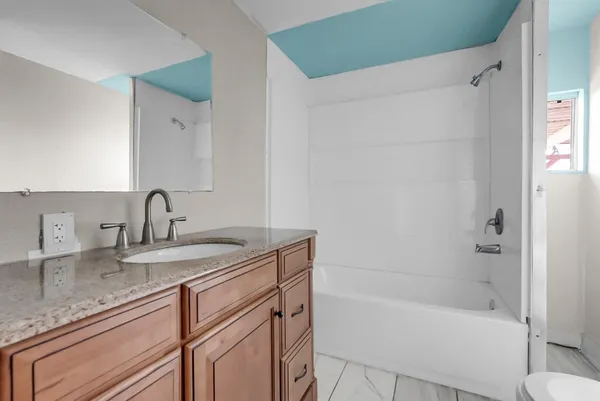 a bathroom with a granite countertop sink and a bathtub
