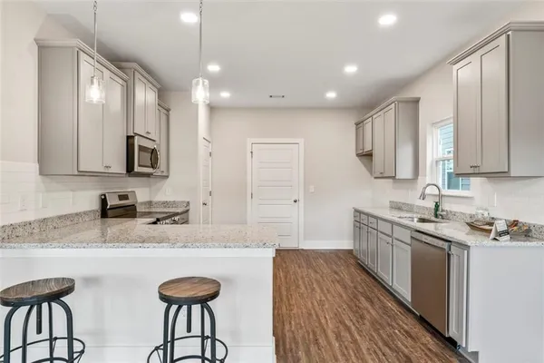 a kitchen with stainless steel appliances granite countertop a sink dishwasher a stove refrigerator and cabinets with wooden floor