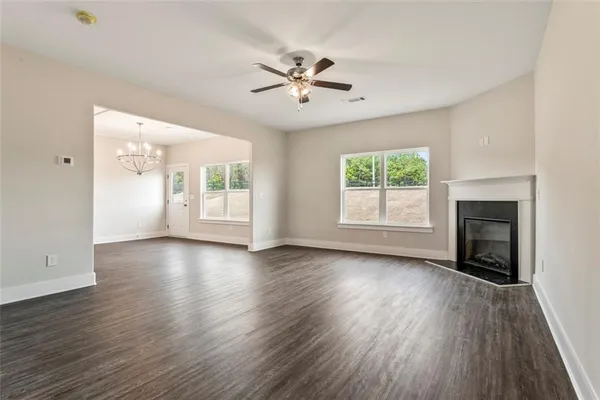 an empty room with wooden floor fireplace and windows