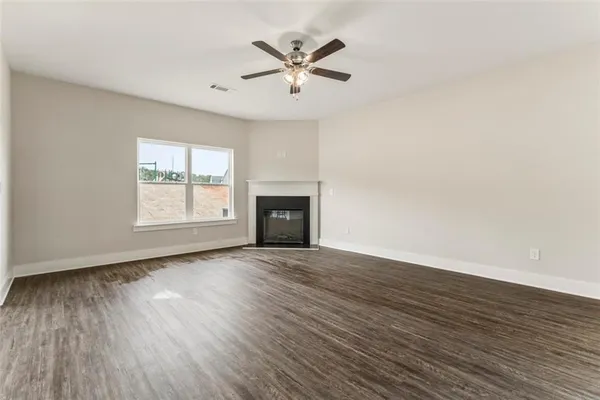an empty room with wooden floor chandelier fan and windows