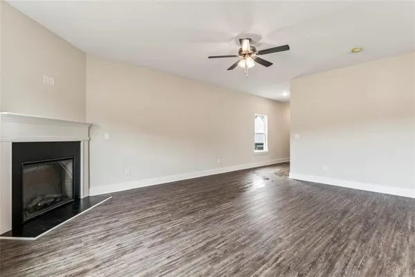 a view of an empty room with wooden floor and a fireplace