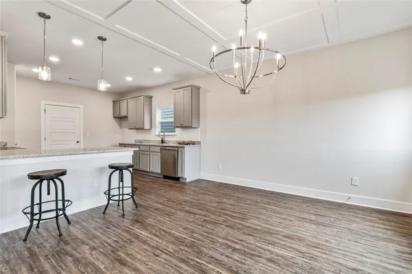 a kitchen with kitchen island stainless steel appliances a dining table chairs sink and cabinets