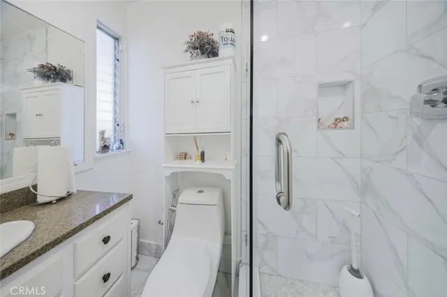 a bathroom with a granite countertop sink a toilet and shower