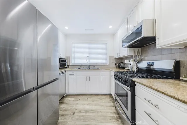 a kitchen with stainless steel appliances granite countertop a stove a sink and a refrigerator
