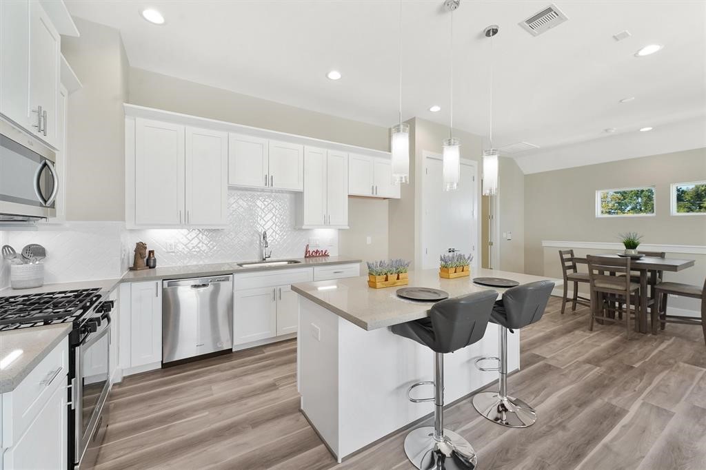 2504 West Tidwell Road, Unit G Houston, TX 77091 - Photo 8 of 30 a kitchen with stainless steel appliances granite countertop a stove top oven a sink dishwasher a dining table and chairs with wooden floor