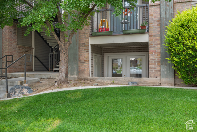 8196 North Cedar Springs Road, Unit 2 Eagle Mountain, UT 84005 - Photo 20 of 22 View of exterior entry featuring a balcony, french doors, a lawn, and brick siding