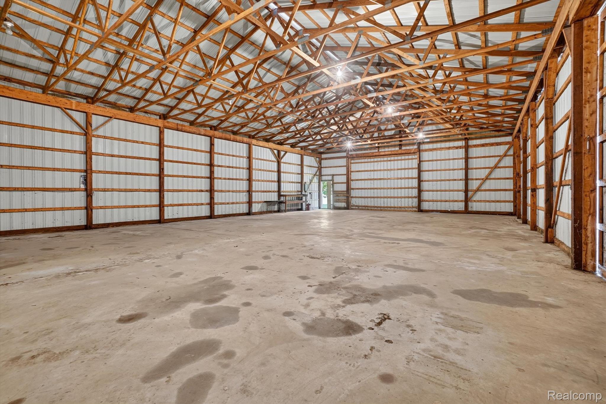 3760 Webberville Road North Williamston, MI 48895 - Photo 54 of 80 Spacious interior featuring a concrete floor, exposed wood beam ceiling, and corrugated metal walls