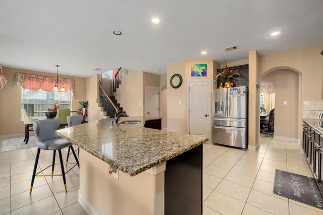 a kitchen with stainless steel appliances kitchen island granite countertop a refrigerator a stove and a sink