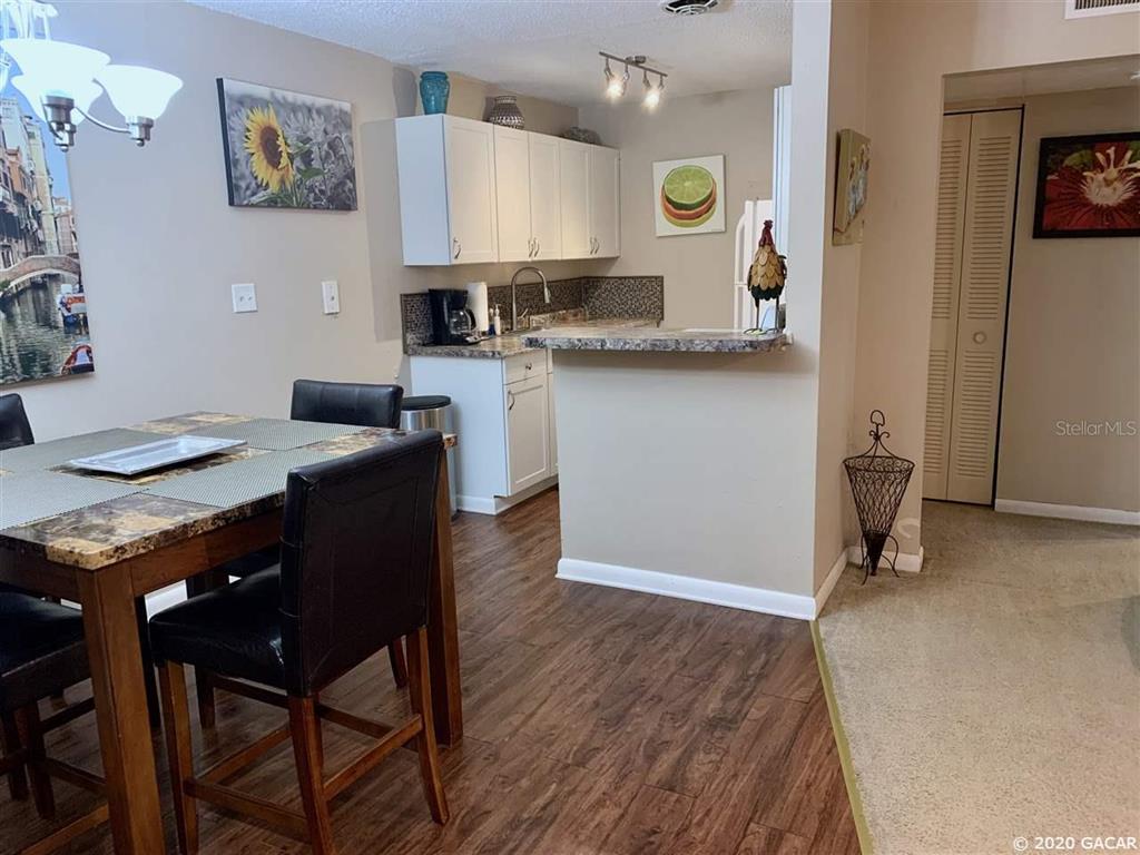 1700 Southwest 16th Court, Unit C26 Gainesville, FL 32608 - Photo 13 of 18 a kitchen with granite countertop cabinets a table and chairs in it