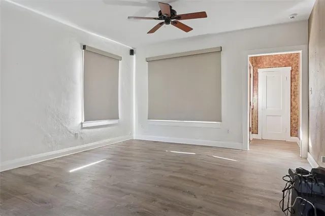 an empty room with wooden floor closet and windows