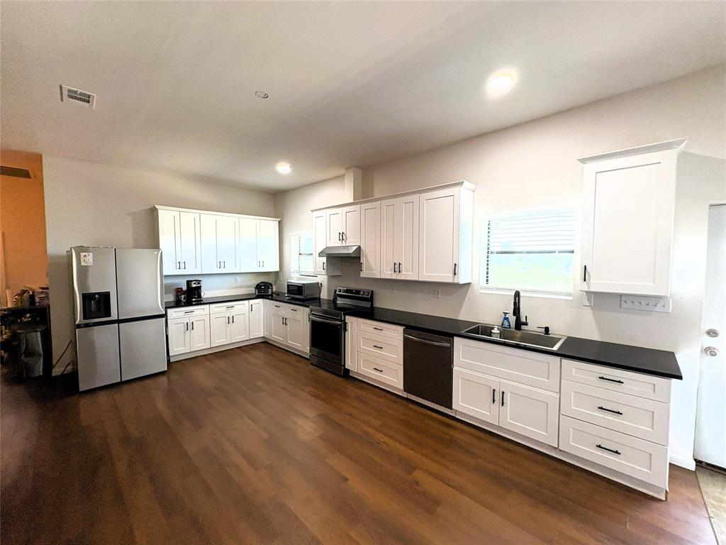 4748 Battle Lake Road Mart, TX 76664 - Photo 6 of 33 Kitchen featuring stainless steel appliances, a sink, dark wood-type flooring, dark countertops, and under cabinet range hood