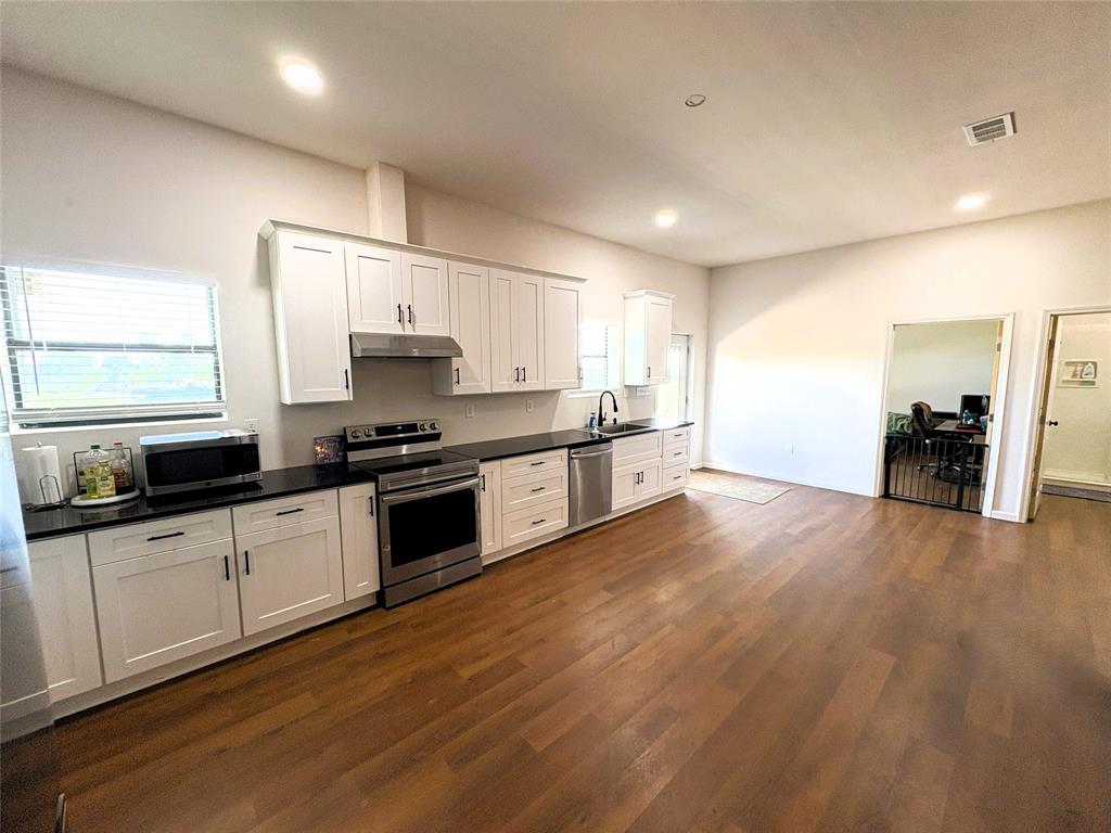 4748 Battle Lake Road Mart, TX 76664 - Photo 7 of 33 Kitchen featuring stainless steel appliances, under cabinet range hood, dark wood-style floors, dark countertops, and a sink
