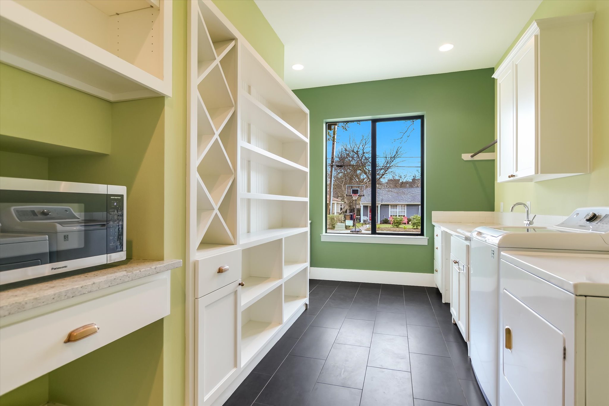 1210 Alguno Road Austin, TX 78757 - Photo 13 of 28 The butler’s pantry pulls double duty with built-in storage, prep space, and a full laundry setup that keeps everyday function feeling polished.