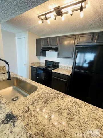 a kitchen with granite countertop a sink stainless steel appliances and view kitchen