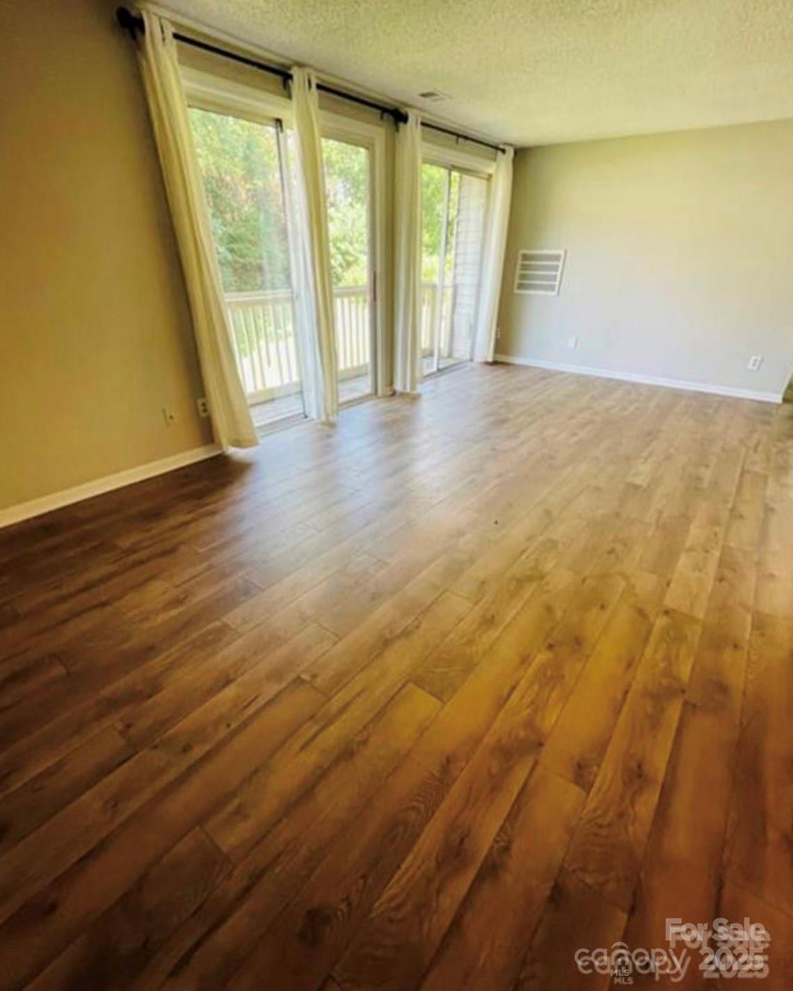 1624 Arlyn Circle, Unit G Charlotte, NC 28213 - Photo 11 of 13 an empty room with wooden floor and windows