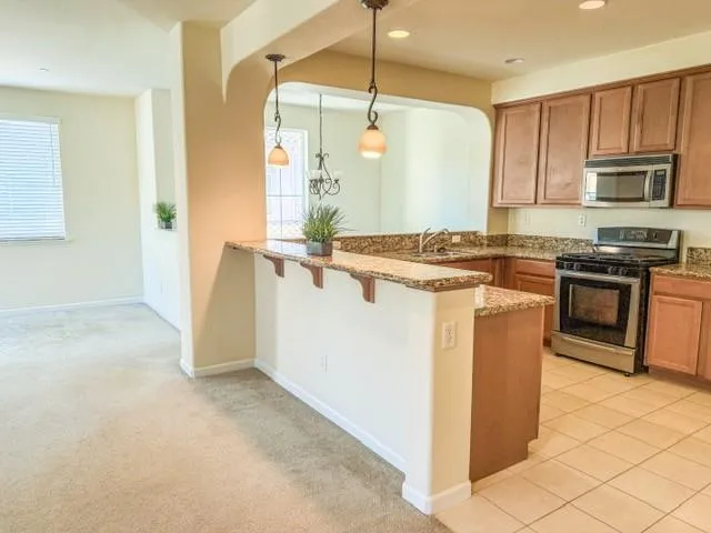 a kitchen with stainless steel appliances granite countertop a stove a sink and a refrigerator