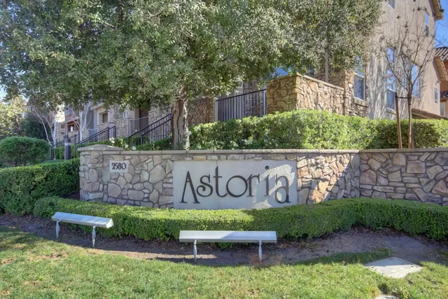 a view of sign board with buildings in background