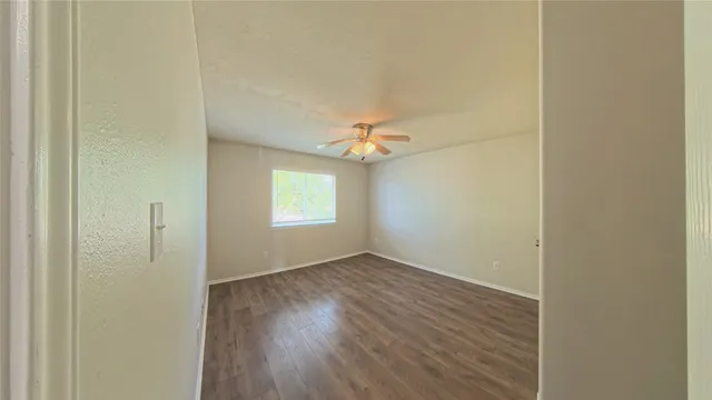 an empty room with a window and wooden floor