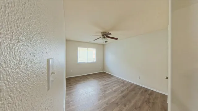 an empty room with wooden floor closet and windows