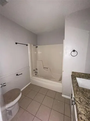 a bathroom with a granite countertop bathtub shower and toilet