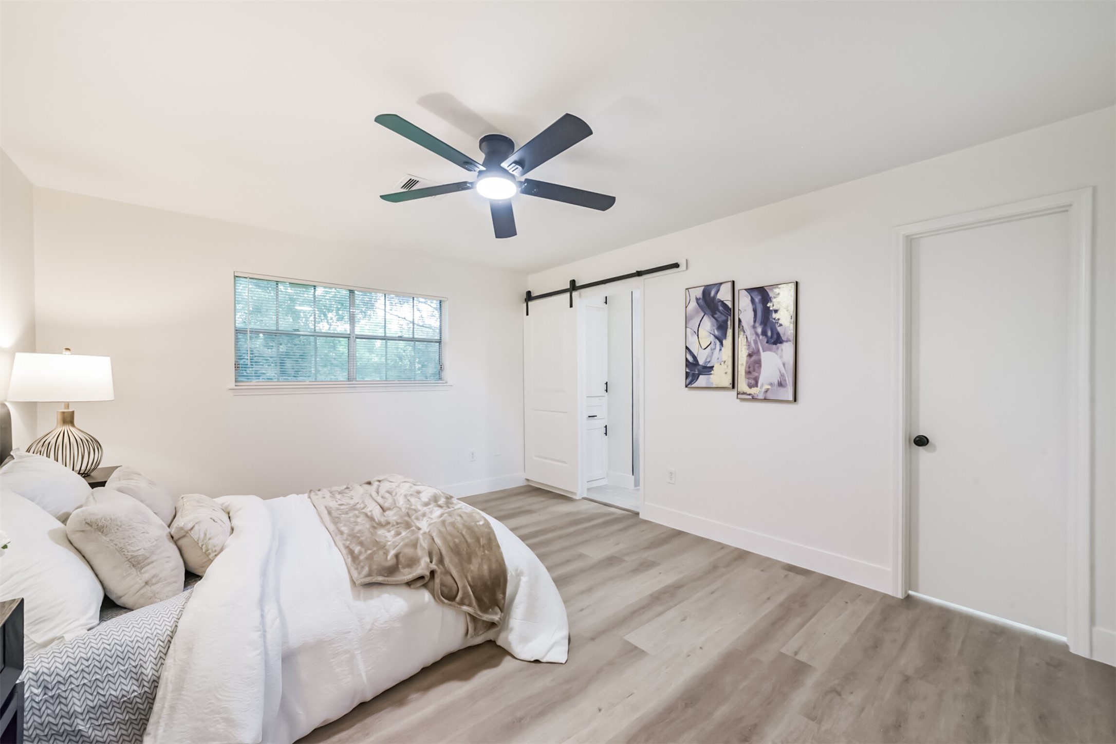 5403 Croix Road Manvel, TX 77578 - Photo 20 of 25 Spacious primary suite featuring updated flooring, modern finishes, stylish barn door accents and a beautifully updated en-suite bath.