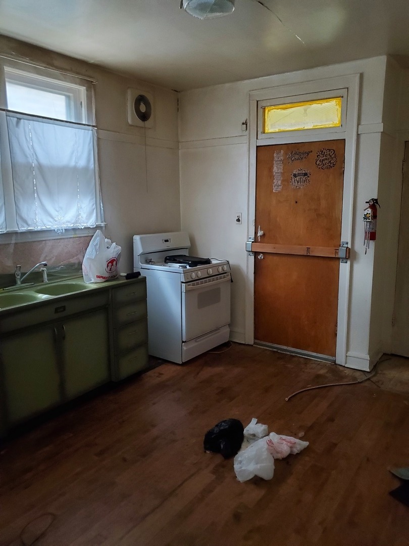 8238 South Rhodes Avenue Chicago, IL 60619 - Photo 3 of 5 a kitchen with a wooden floor and a refrigerator