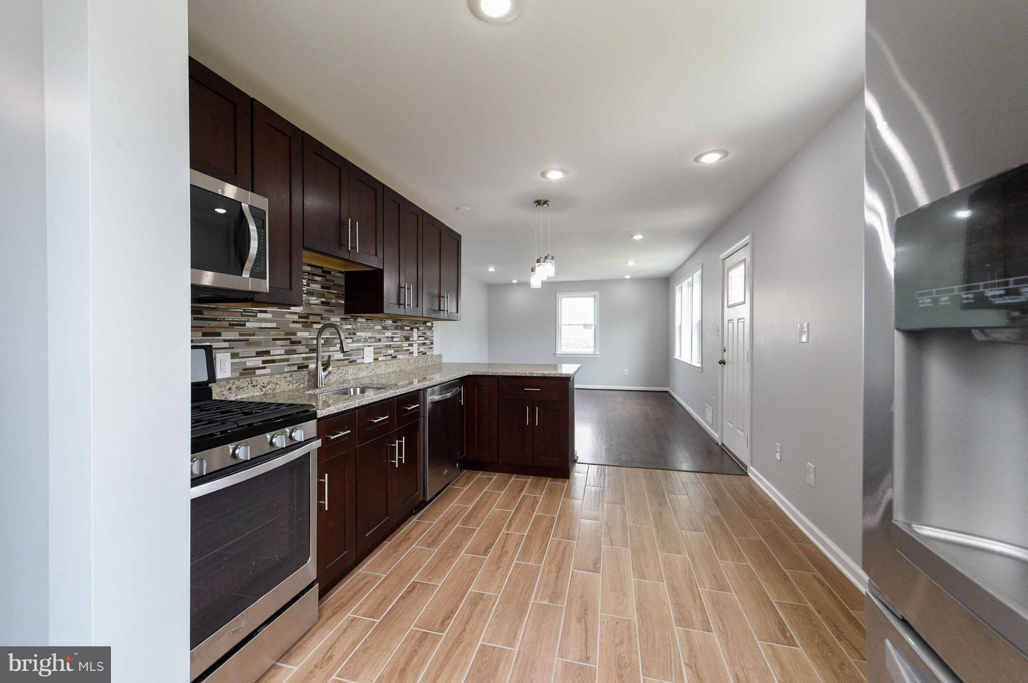3822 Byfield Road Baltimore, MD 21207 - Photo 4 of 30 a large kitchen with stainless steel appliances granite countertop a large stove a sink dishwasher and a refrigerator with wooden floor