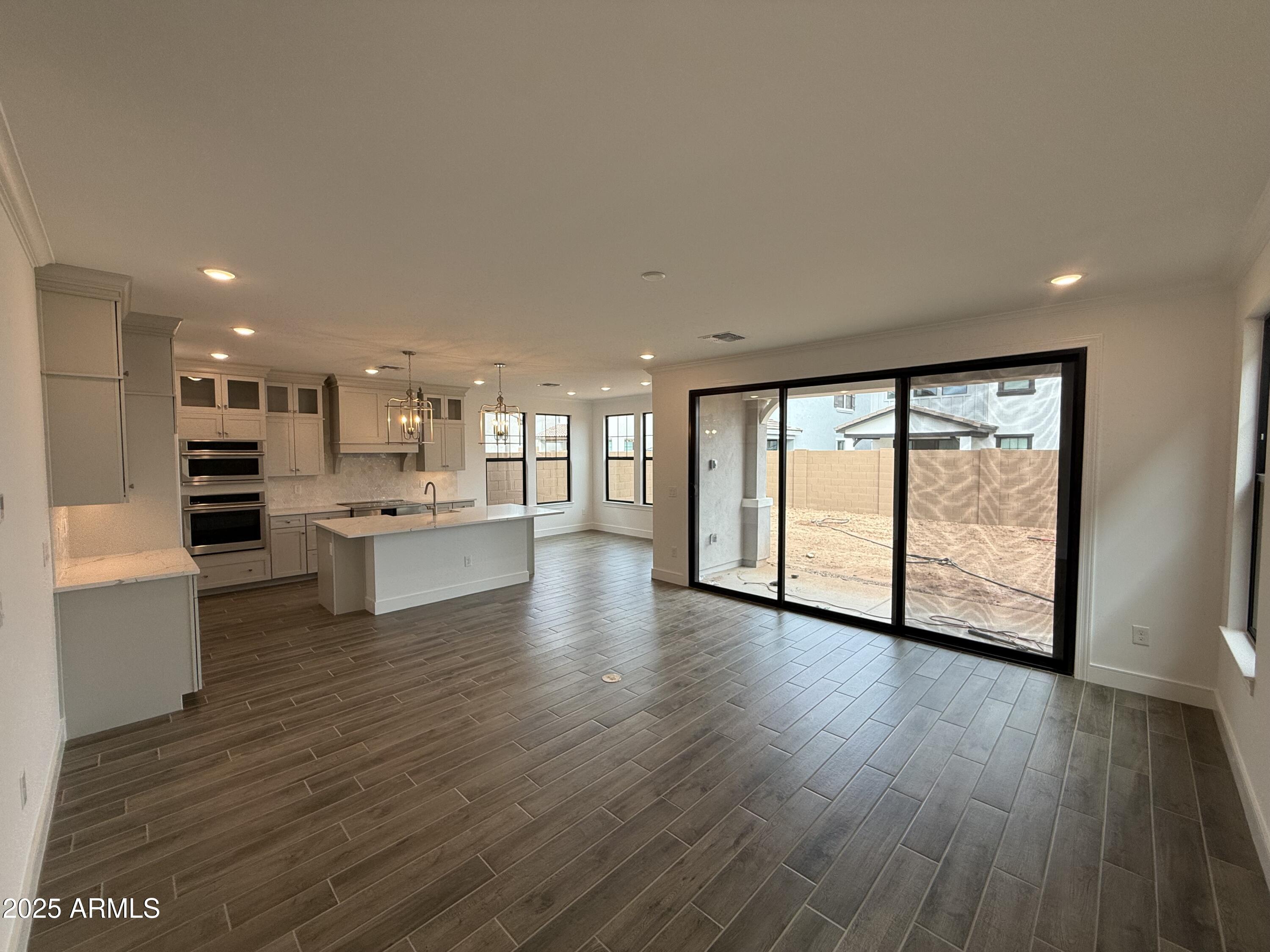 2390 West Los Arboles Place Chandler, AZ 85224 - Photo 2 of 41 a view of an empty room with wooden floor and a kitchen